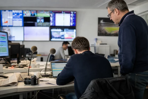 Rédaction parisienne avec journalistes, écrans de scores flous et matériel de presse autour d’un article sur le Mondial 2026