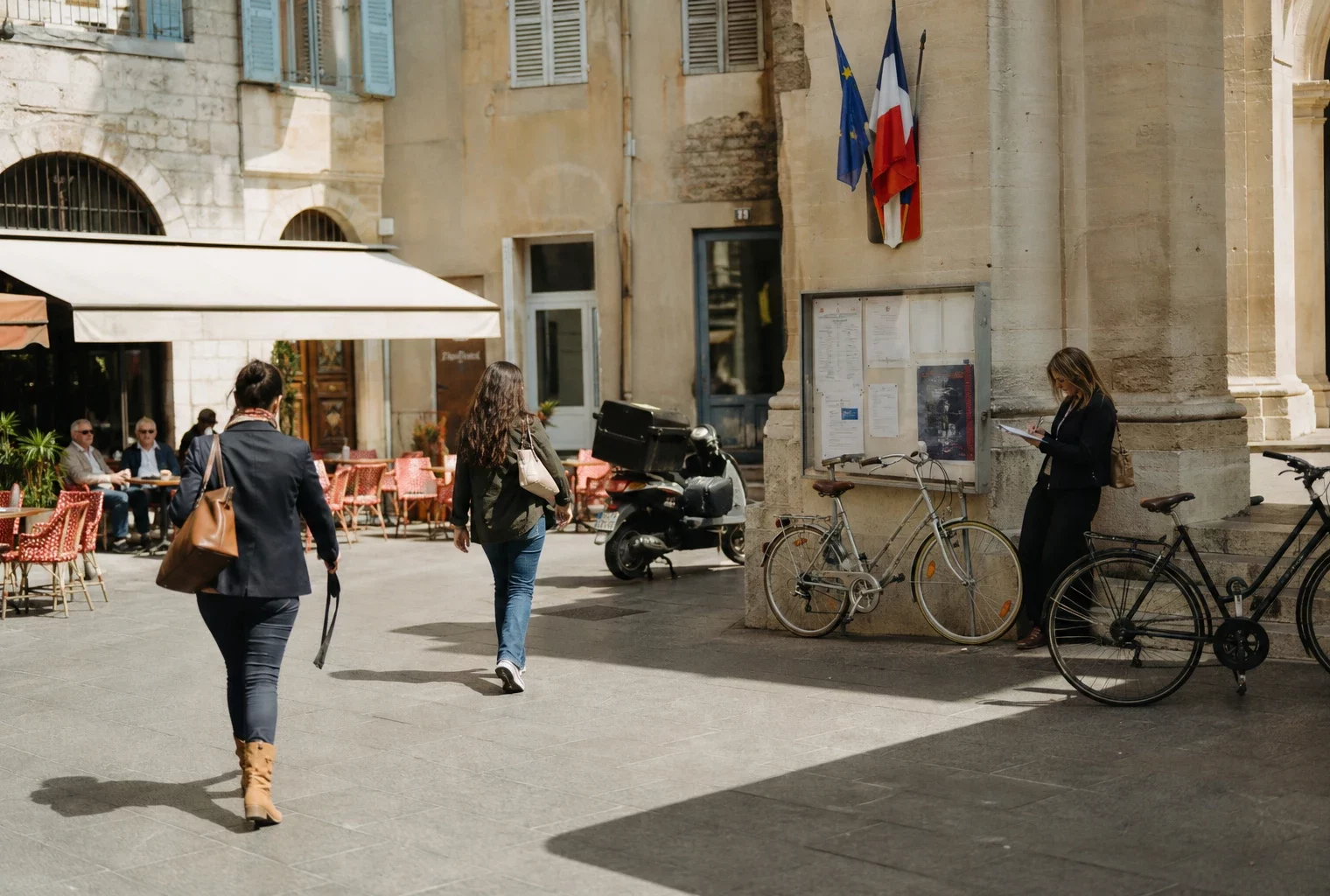 Scène de rue à Nice près d’une mairie, avec habitants anonymes et journaliste en reportage.