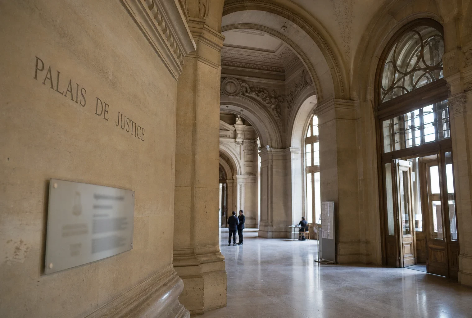 Hall vide du Palais de Justice à Paris, lumière naturelle claire et ambiance institutionnelle sobre.