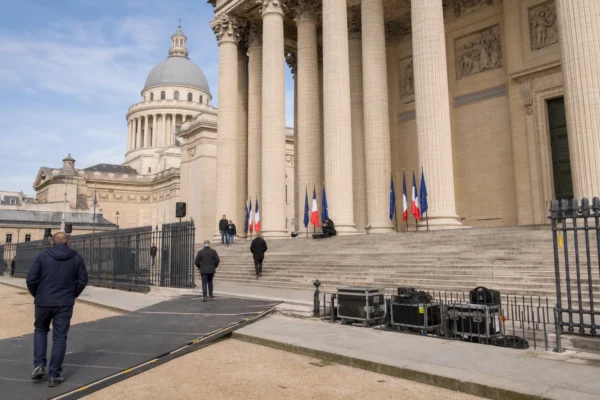 Le Panthéon à Paris pendant la préparation d’une cérémonie, avec des silhouettes anonymes et un accès sécurisé calme.