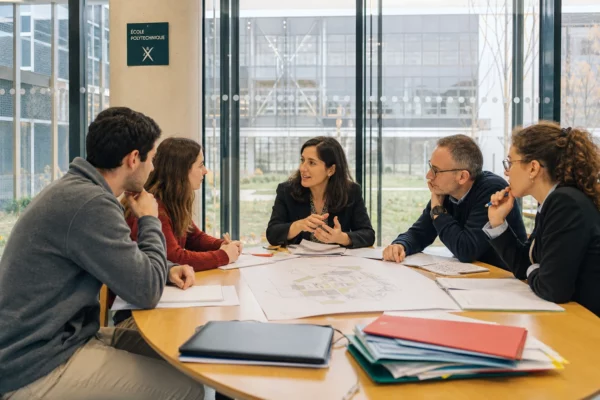 Réunion à Polytechnique autour d’un projet d’institut de recherche, avec plans d’architecture et ambiance de campus