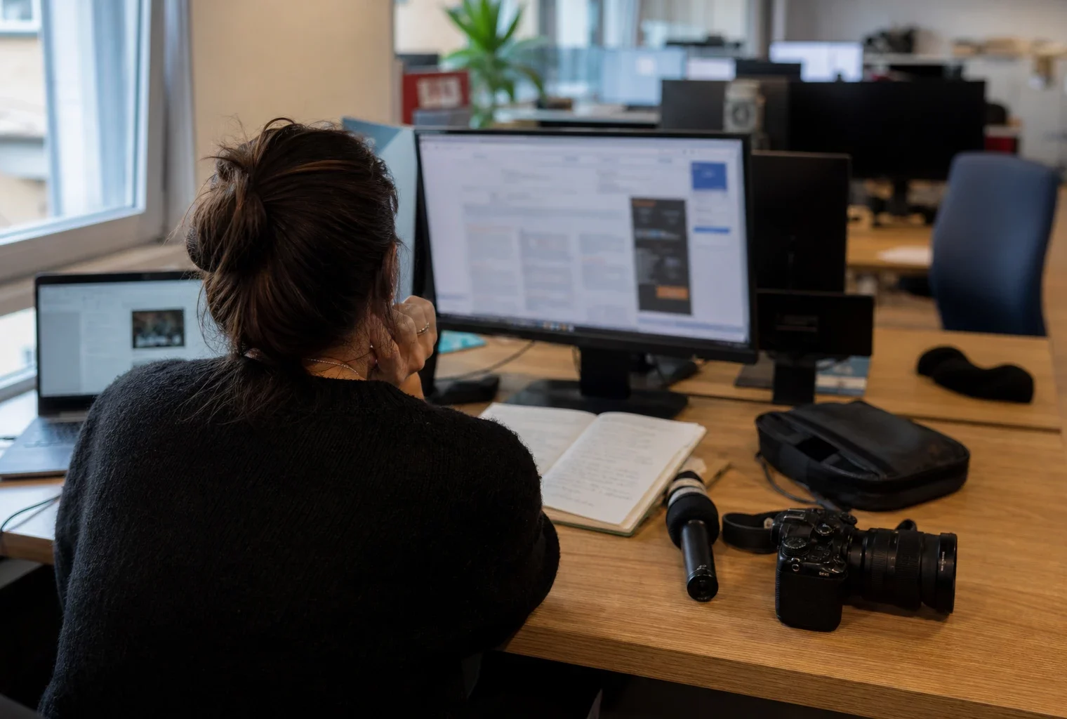 Journaliste en rédaction préparant un sujet sur l’affaire Lyhanna avec micro, carnet et écrans flous