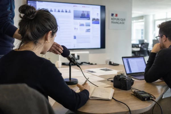 Rédaction politique lumineuse avec journaliste, micro et écrans flous préparant un sujet sur la Corse