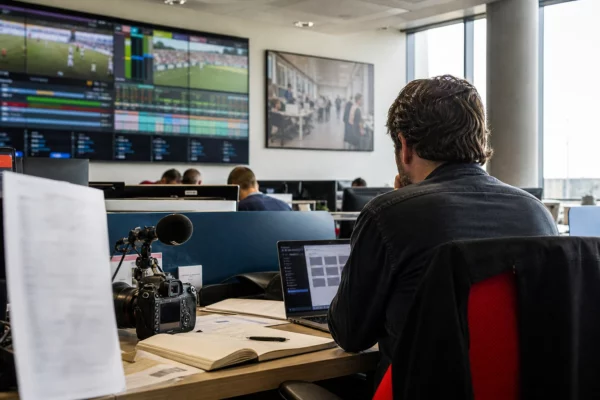 Rédaction française avec un journaliste, des écrans flous et du matériel de presse pour un suivi du Mondial 2026