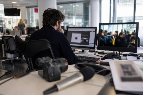 Journaliste dans une rédaction française, avec caméra, micro et écrans flous sur le thème de l’enseignement supérieur privé.
