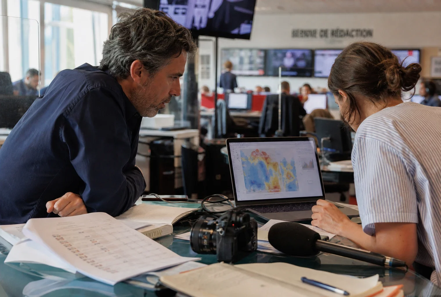 Une rédaction française prépare un sujet sur la chaleur du Mondial 2026, avec écrans flous et journaliste au travail.