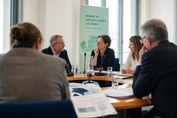 Réunion européenne sobre avec plusieurs personnes autour d’une table et des dossiers, dans une lumière naturelle claire.