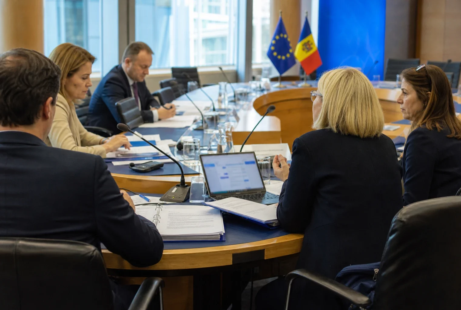 Réunion européenne à Bruxelles avec plusieurs délégués autour d’une table, dossiers ouverts et petits drapeaux discrets.