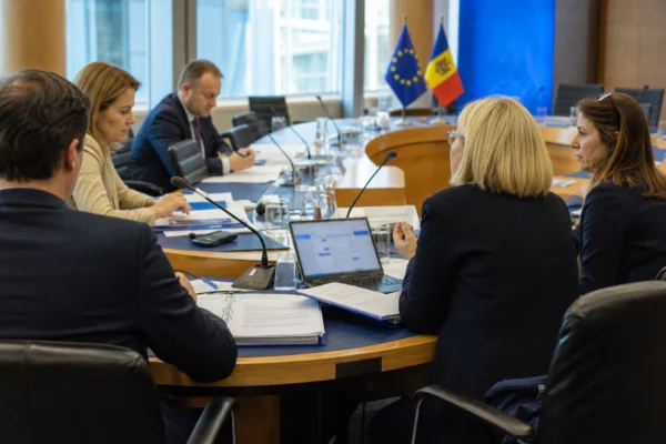 Réunion européenne à Bruxelles avec plusieurs délégués autour d’une table, dossiers ouverts et petits drapeaux discrets.