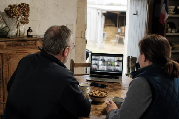 Réunion politique en visio dans une ferme française, autour d’une table de cuisine avec un ordinateur portable ouvert.