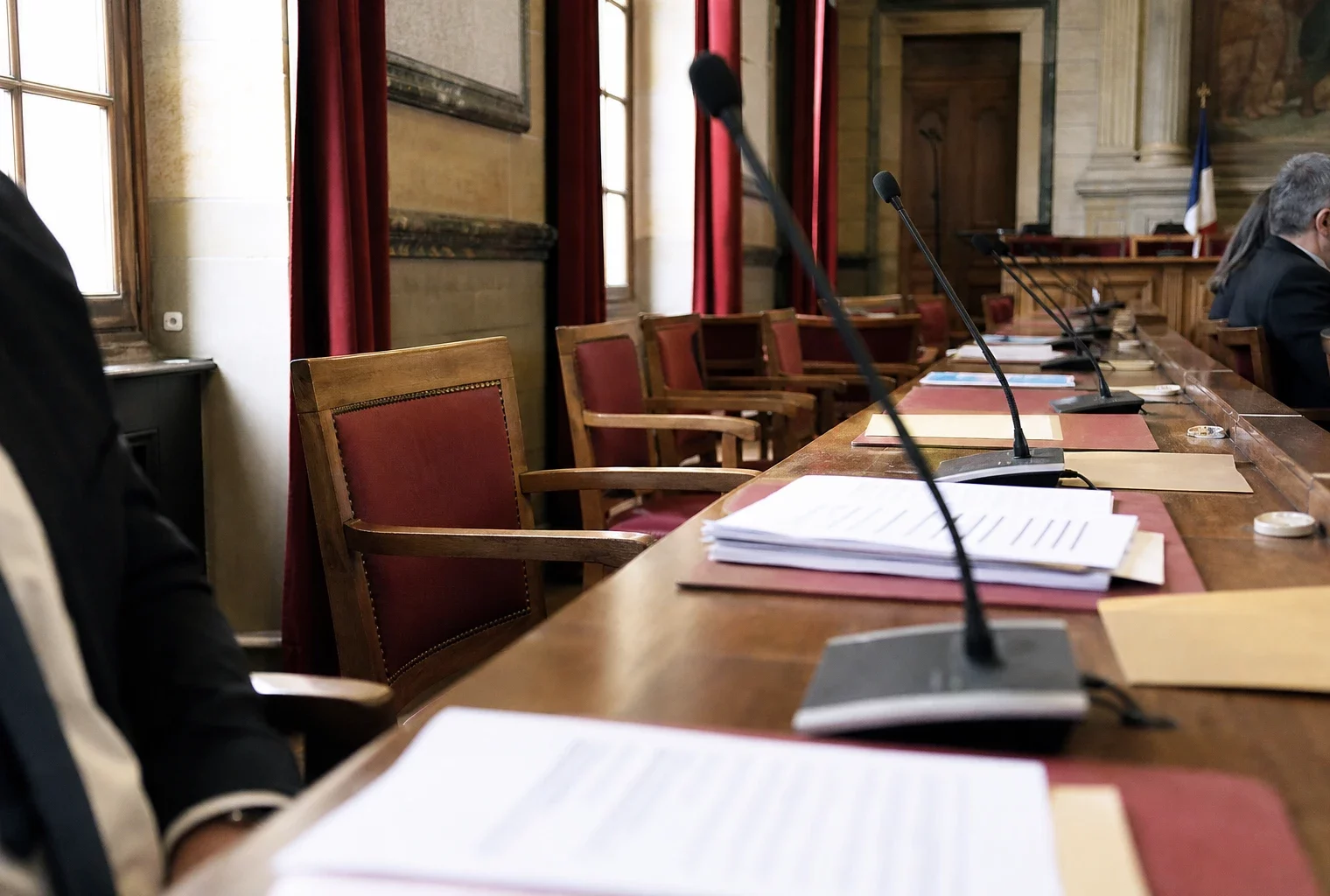 Salle municipale française avec micros, dossiers et chaise vide lors d’un débat institutionnel sur le don d’organes