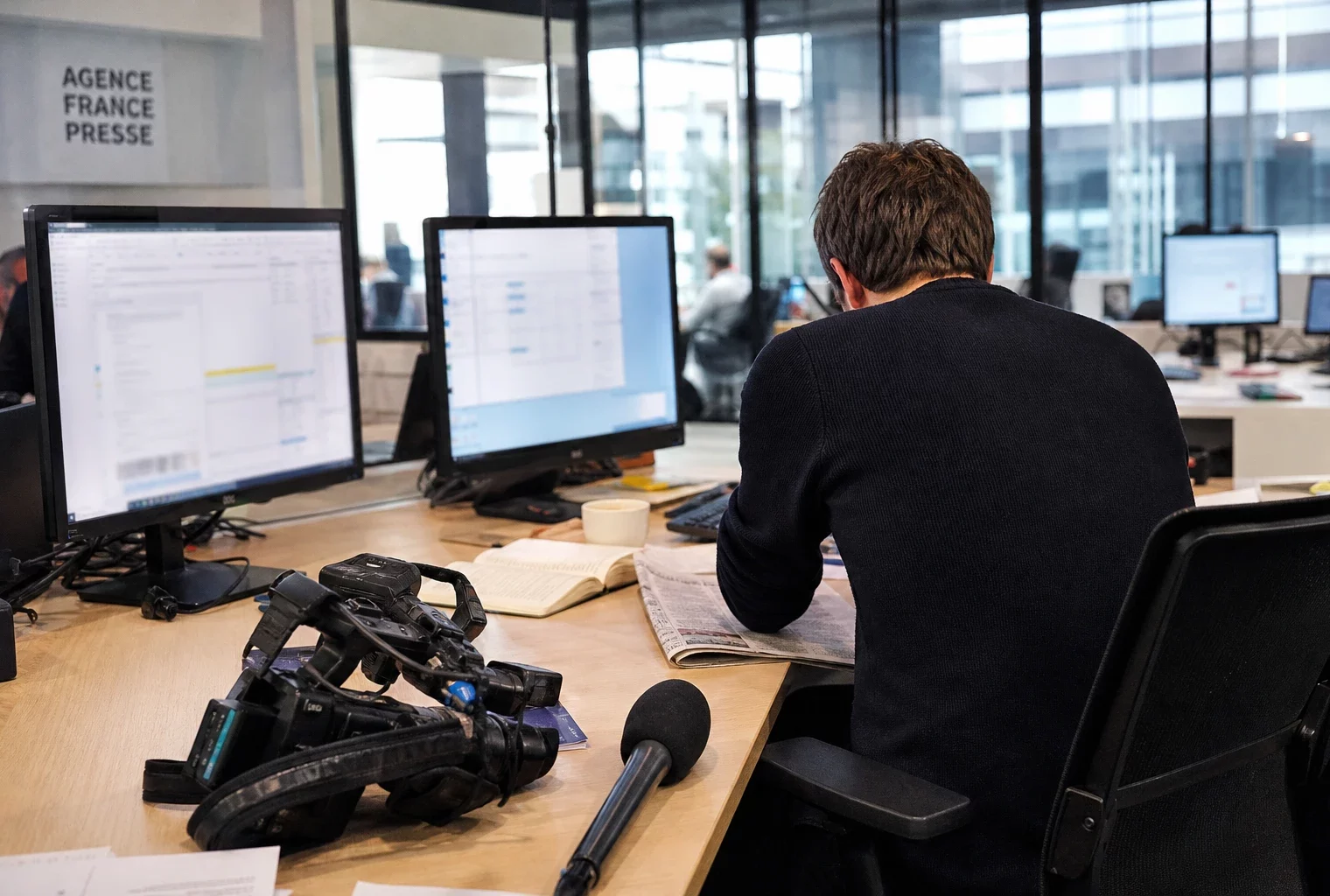 Reporter en salle de rédaction, caméra et écrans flous, pour illustrer la présidence irlandaise de l’Union européenne.
