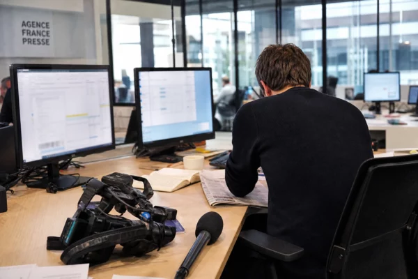 Reporter en salle de rédaction, caméra et écrans flous, pour illustrer la présidence irlandaise de l’Union européenne.