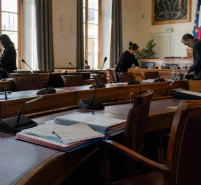Salle municipale parisienne avec micros, chaises vides et dossiers après une soirée de tension à Nuit Blanche