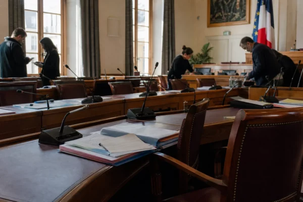 Salle municipale parisienne avec micros, chaises vides et dossiers après une soirée de tension à Nuit Blanche