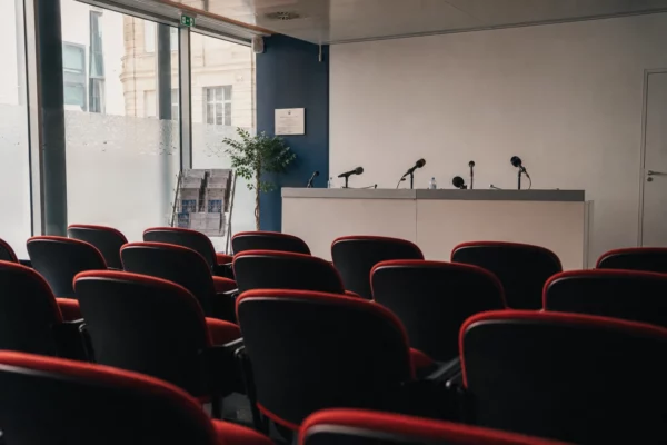 Salle de presse institutionnelle vide à Paris, avec pupitre, micros et rangées de chaises avant un grand tournoi.