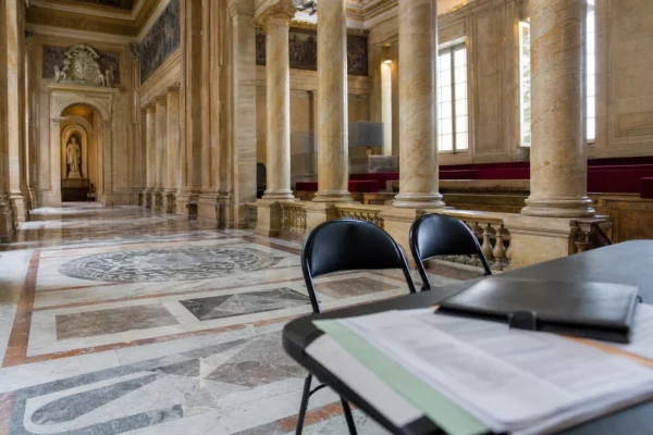 Salle vide de l’Assemblée nationale avec dossiers fermés, illustrant la stratégie présidentielle de Mélenchon.