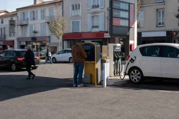 Station-service française de quartier, voitures en ravitaillement et ambiance calme sur fond de ville moyenne.