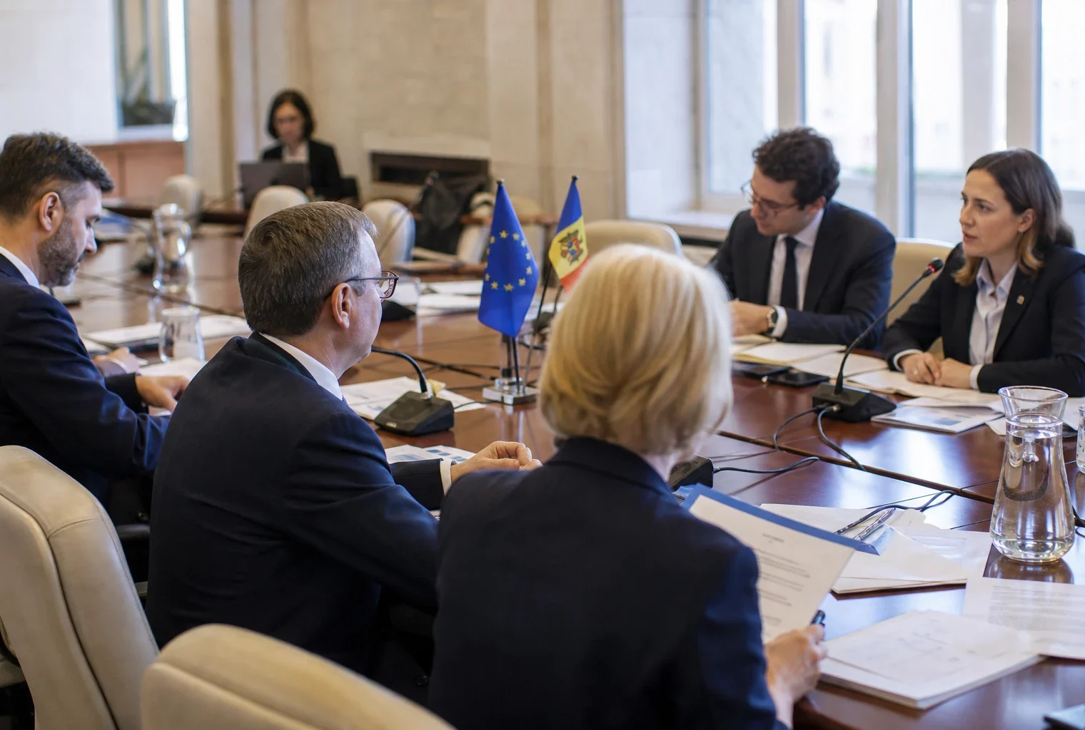 Réunion institutionnelle UE-Moldavie à Chișinău avec dossiers, micros de table et drapeaux discrets.