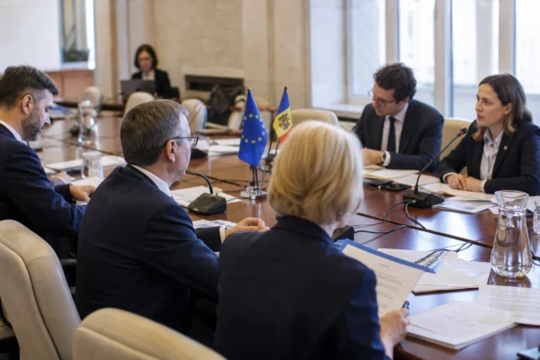 Réunion institutionnelle UE-Moldavie à Chișinău avec dossiers, micros de table et drapeaux discrets.