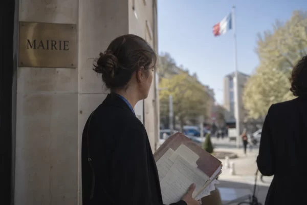 Un collaborateur politique anonyme tient un dossier devant un bâtiment civique, dans une rue calme d’Ankara.