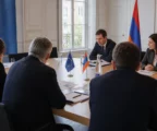 Réunion diplomatique sobre entre représentants européens et arméniens autour d’une table avec dossiers et petits drapeaux.