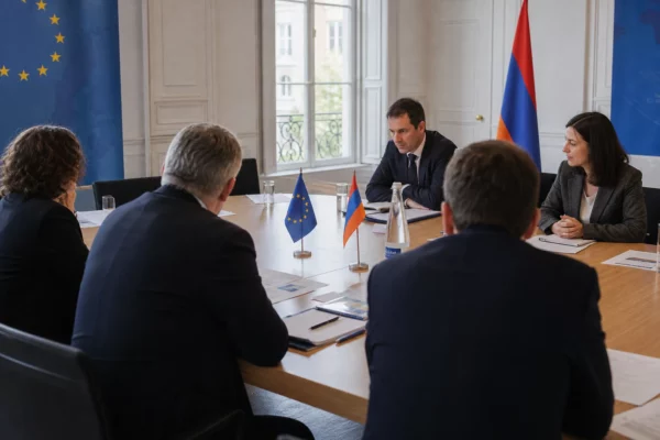 Réunion diplomatique sobre entre représentants européens et arméniens autour d’une table avec dossiers et petits drapeaux.
