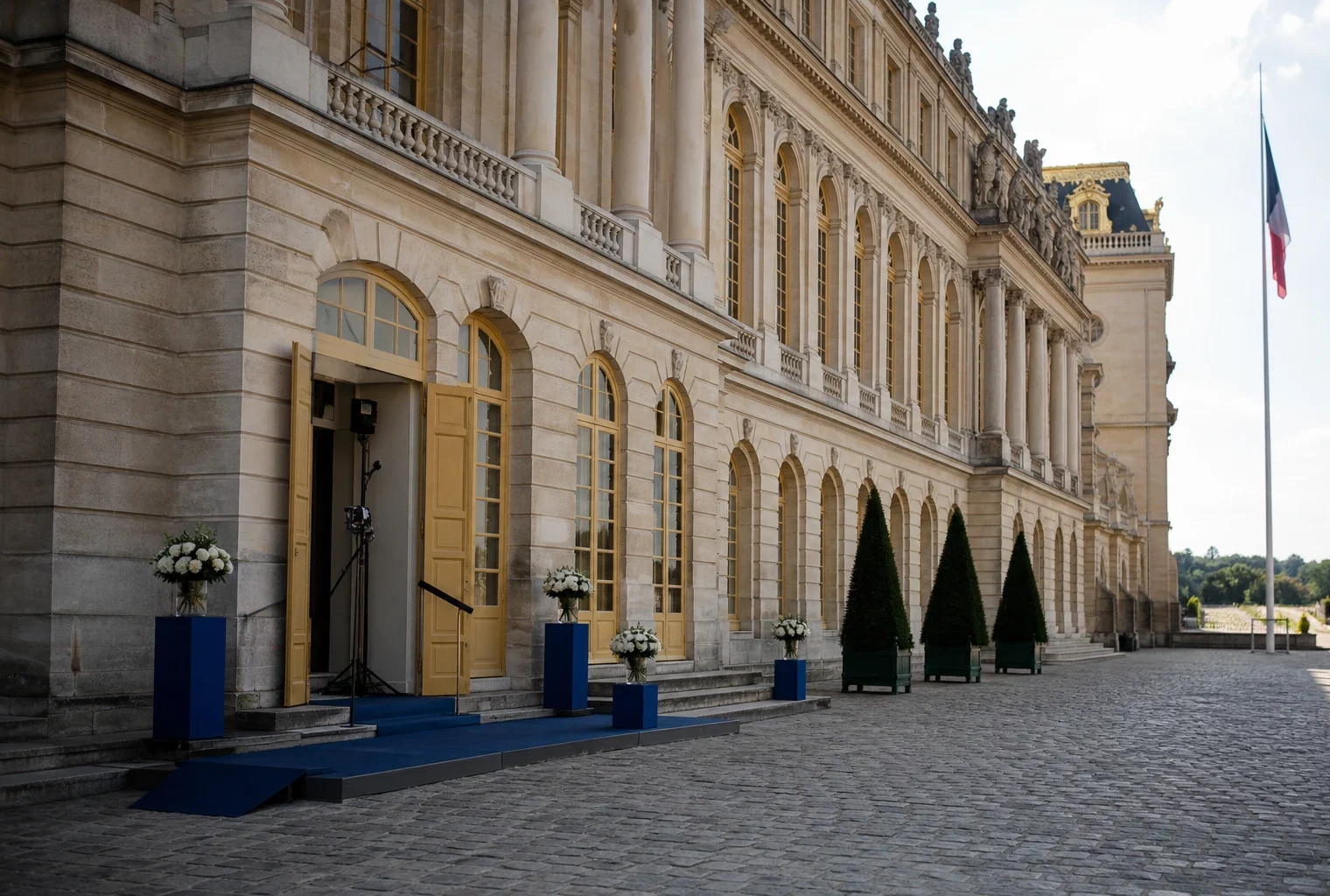 Façade du château de Versailles en lumière claire, avec un discret drapeau tricolore au loin et une ambiance diplomatique.