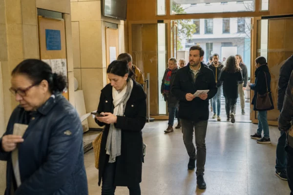 Des passants anonymes entrent dans un lieu municipal lumineux à Saint-Denis, dans une ambiance de campagne calme.