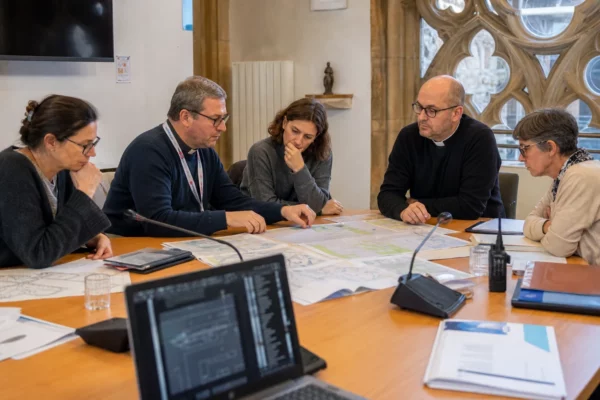 Réunion de préparation à Metz avec des organisateurs anonymes autour de plans et micros, près du quartier cathédral.