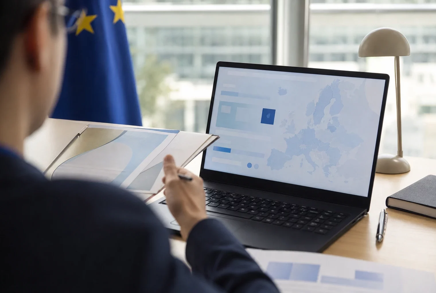 Vue de dos sur un écran d’ordinateur affichant une interface européenne abstraite, dans un bureau lumineux