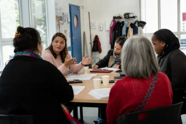 Des adultes anonymes participent à un atelier associatif lumineux dans un centre de quartier français.