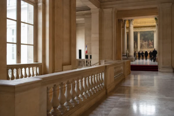 Couloir de l’Assemblée nationale vu en oblique, lumière naturelle claire et ambiance de tension parlementaire.
