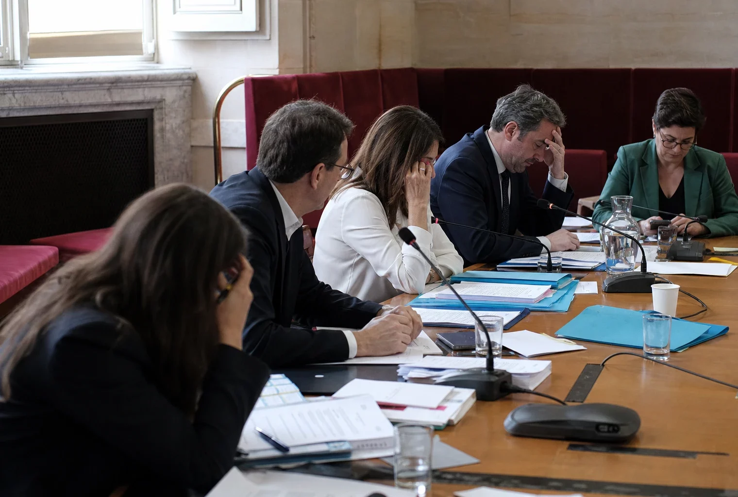 Députés anonymes en commission à l’Assemblée nationale, autour de microphones et dossiers, dans une ambiance de vote fragmenté.