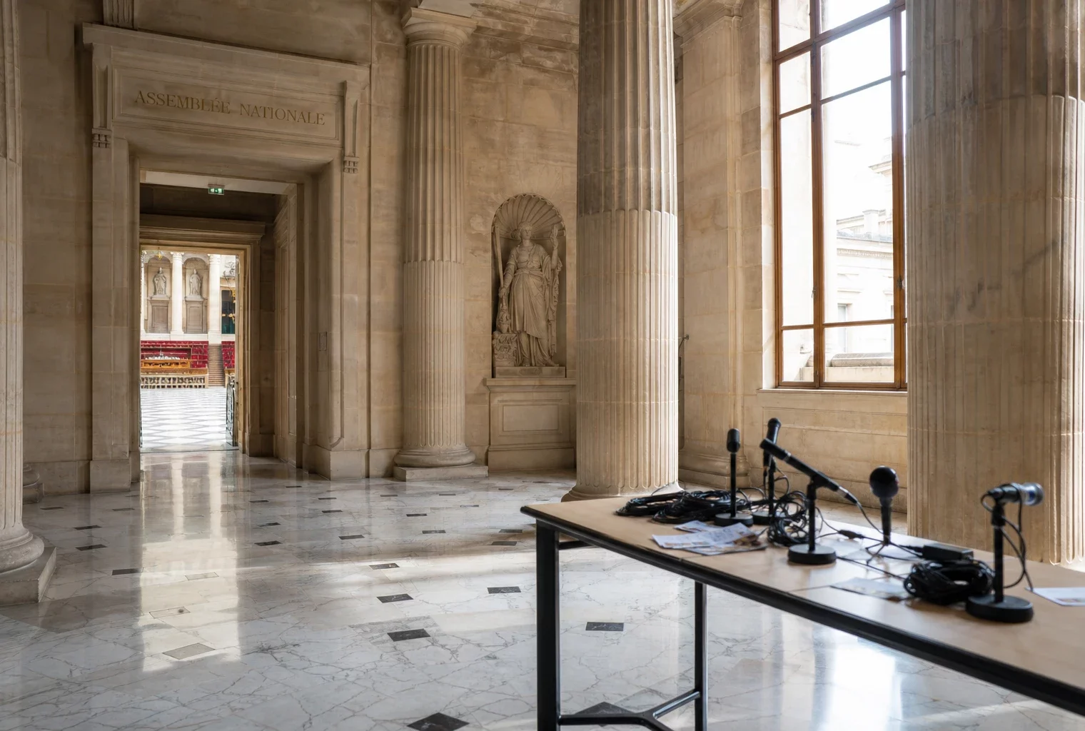 Salle des Quatre-Colonnes vide de l’Assemblée nationale, vue en oblique, avec lumière naturelle sur le marbre.