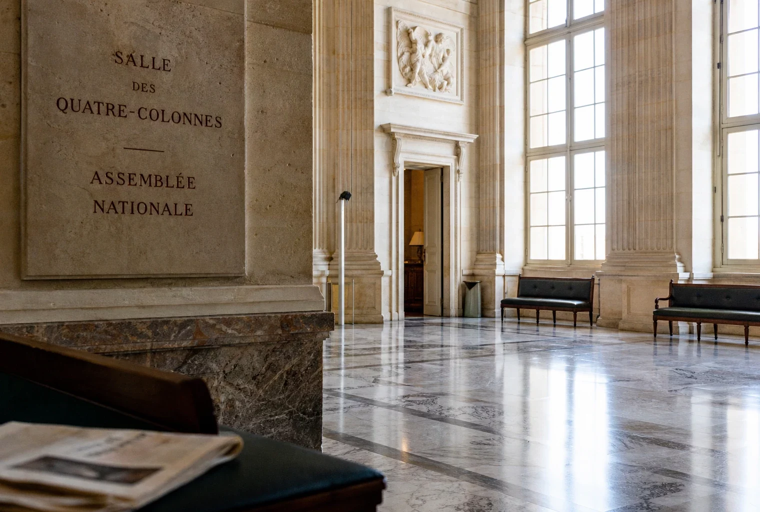 Salle vide de l’Assemblée nationale en lumière naturelle, avec marbre clair et ambiance institutionnelle calme.
