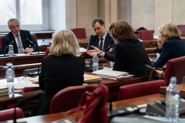 Audition parlementaire en commission sur l’Europe, avec micros, dossiers et silhouettes anonymes dans l’Assemblée.