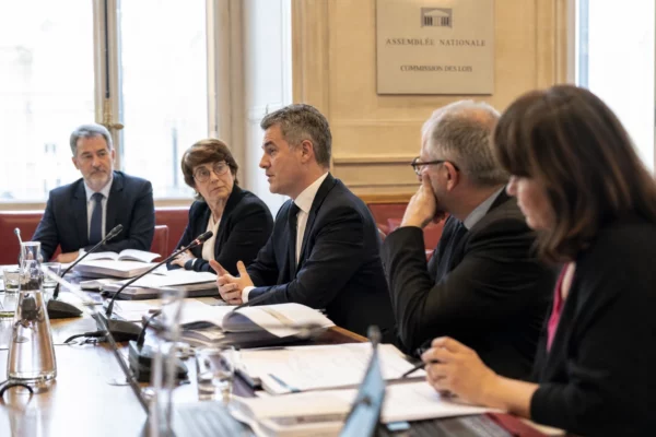 Audition parlementaire sur le Défenseur des droits, avec micros, dossiers ouverts et silhouettes anonymes en commission.