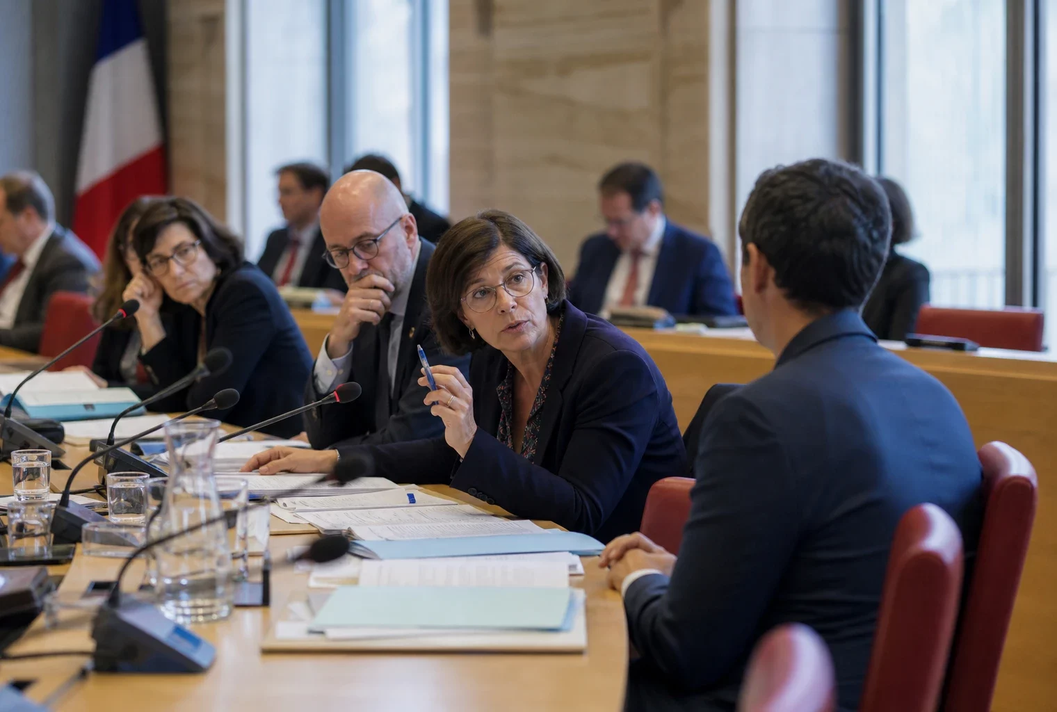 Audition parlementaire sur la protection des enfants avec micros, dossiers ouverts et silhouettes anonymes en commission