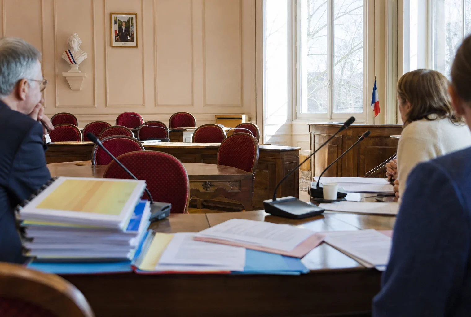 Salle municipale avec micros, dossiers et chaise vide symbolisant l’avocat automatique pour les enfants protégés.