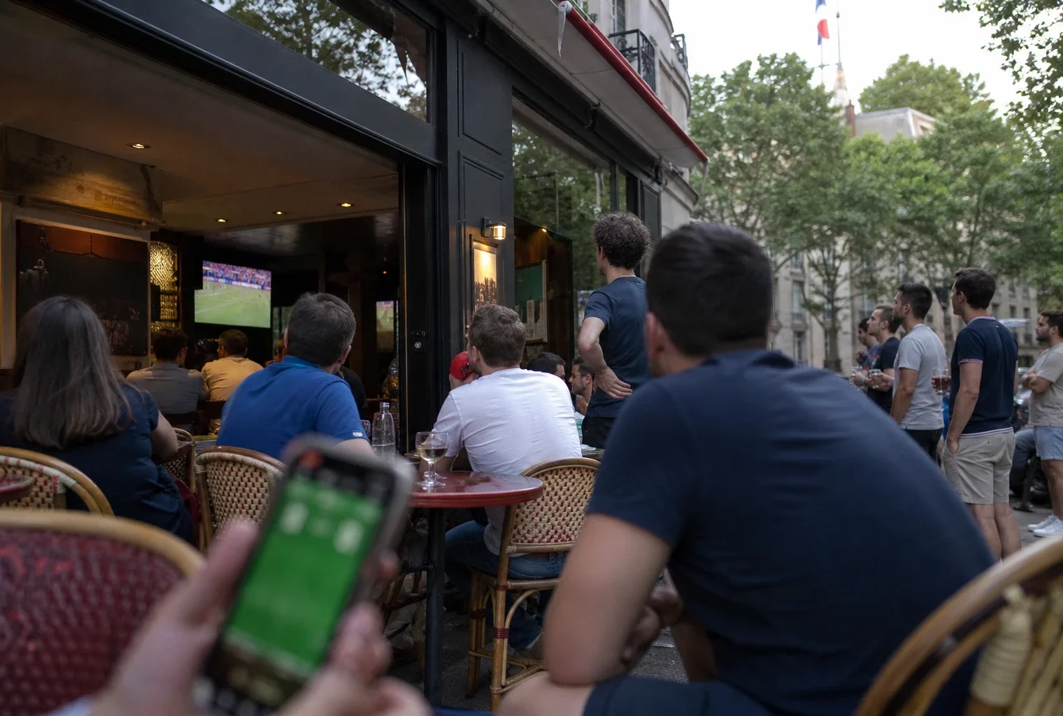 Supporters français dans un café de quartier regardant la finale de la Coupe du monde sur un écran intérieur.