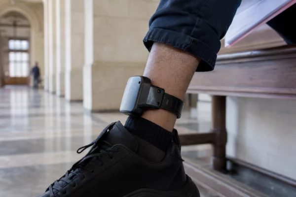 Gros plan sur un bracelet électronique à la cheville dans un couloir de tribunal français, lumière naturelle claire