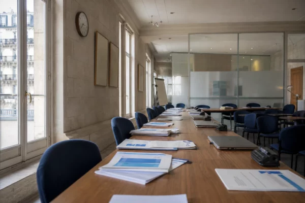 Salle de réunion lumineuse dans un bureau de sondage parisien, avec dossiers et ordinateurs, en ambiance institutionnelle calme.