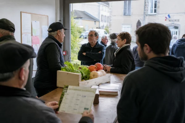 Des habitants dans une mairie rurale près d’une coopérative, avec un calendrier flou et des produits agricoles.