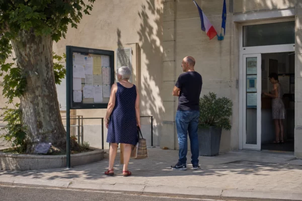 Des habitants arrivent devant une mairie française par forte chaleur, dans une scène de service public lumineuse et réaliste.