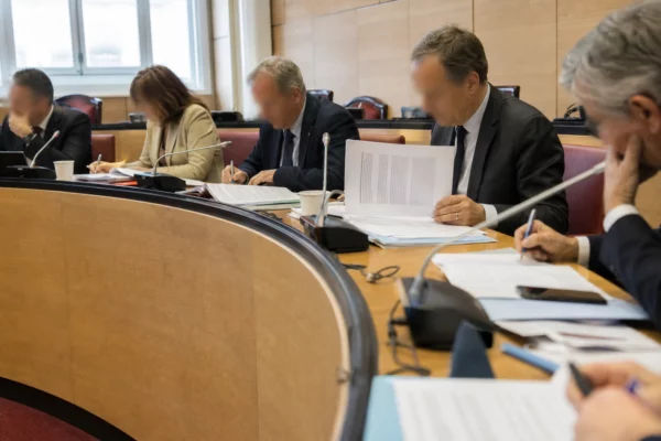 Réunion de commission parlementaire avec dossiers et micros autour des avantages accordés aux anciens Premiers ministres