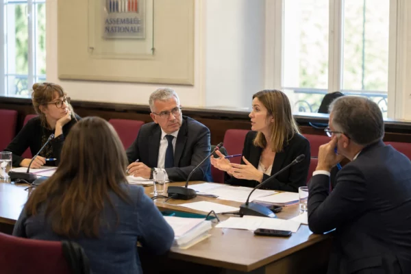 Audition parlementaire sur la canicule dans une salle de commission, avec micros, dossiers et cinq personnes anonymes
