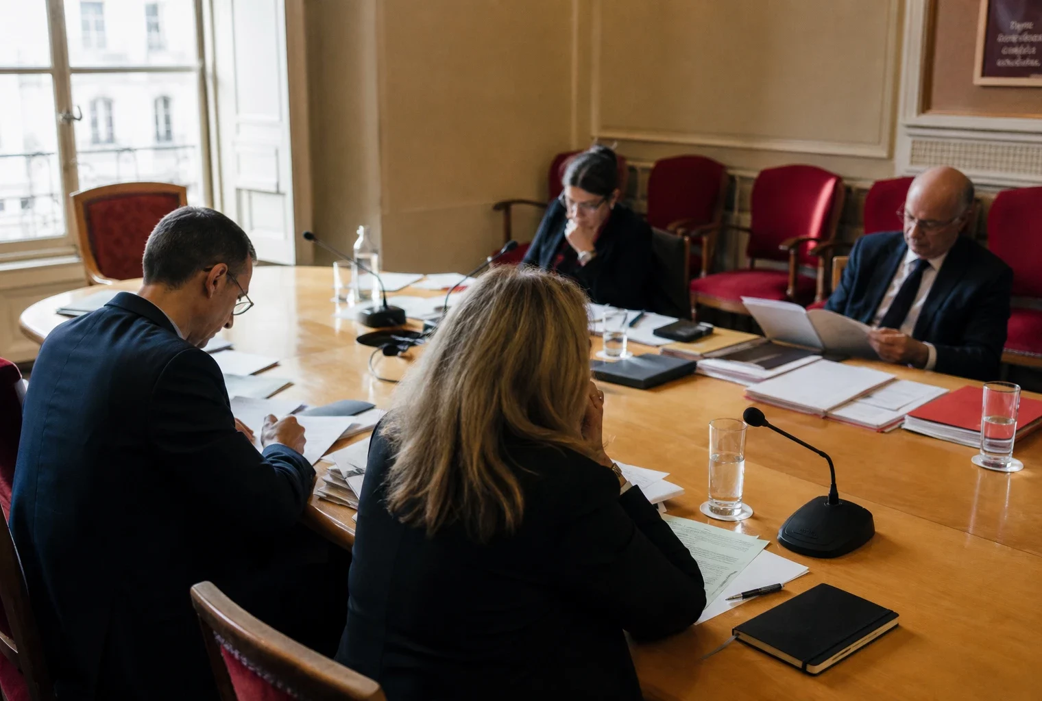 Réunion parlementaire française sur la défense dans une salle de commission, avec micros, dossiers et plusieurs silhouettes anonymes.