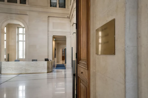 Hall institutionnel lumineux et porte sobre évoquant le Conseil constitutionnel, en photo de presse réaliste.