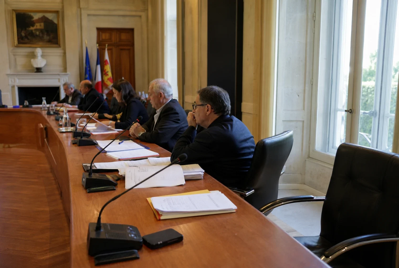 Salle municipale avec micros, dossiers et chaise vide, dans une ambiance de conseil local liée aux incendies en Gironde